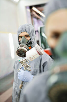 Fahrzeugtechnik: Auszubildender mit Lackierpistole 