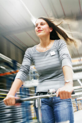 Logistik im Unternehmen: Mitarbeiterin auf Betriebsroller in Bewegung 