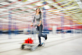 Logistik im Unternehmen: Mitarbeiterin auf Betriebsroller in Bewegung 